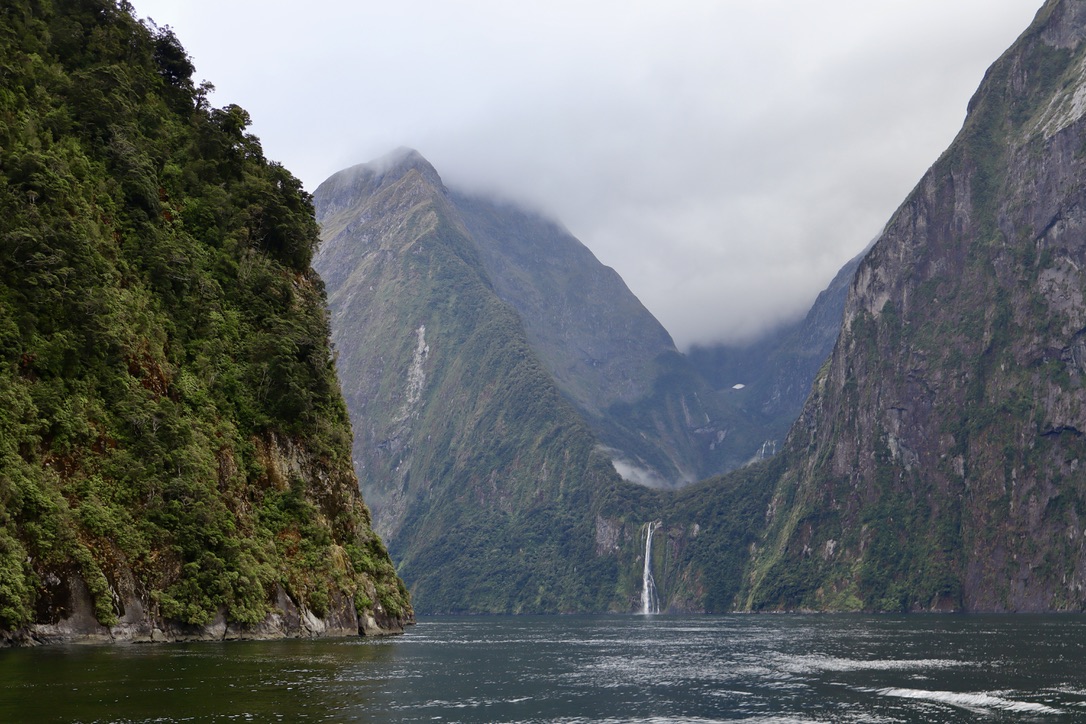 waterfall between two mountains on a misty day