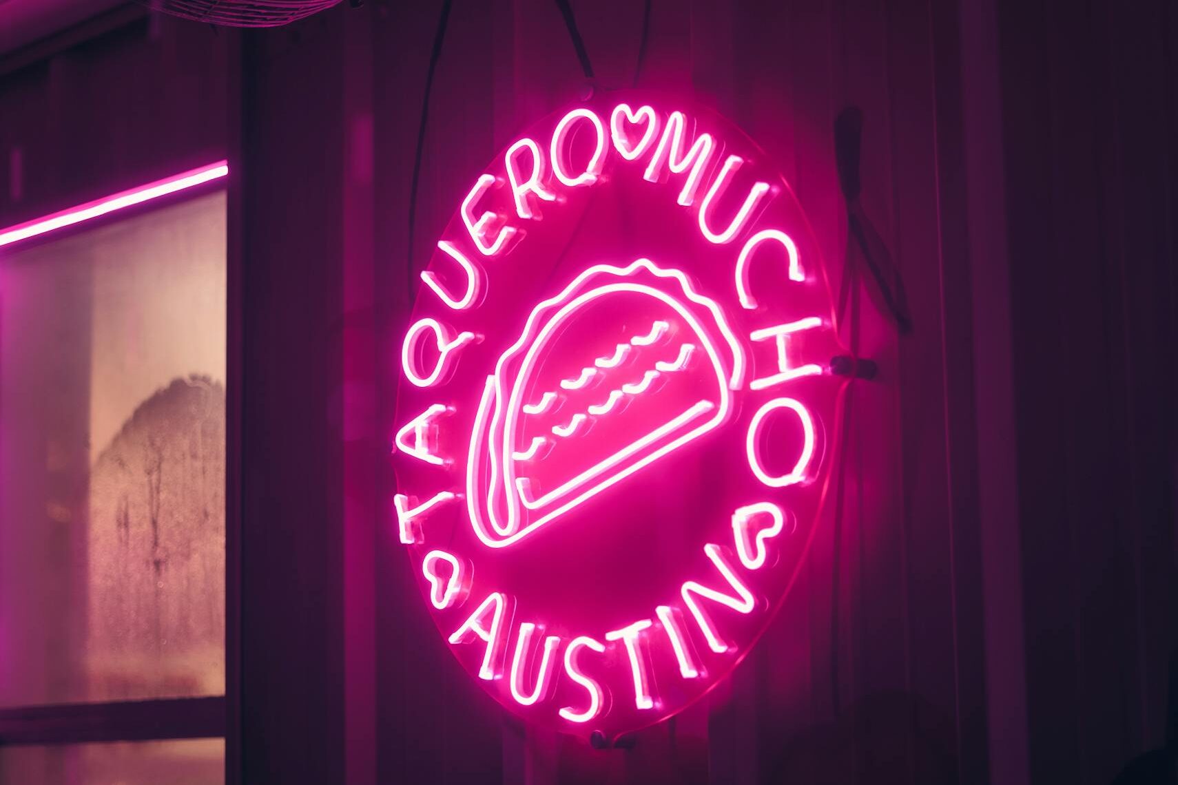 Bright pink neon sign of a taco displayed at Taquero Mucho, Austin, Texas.