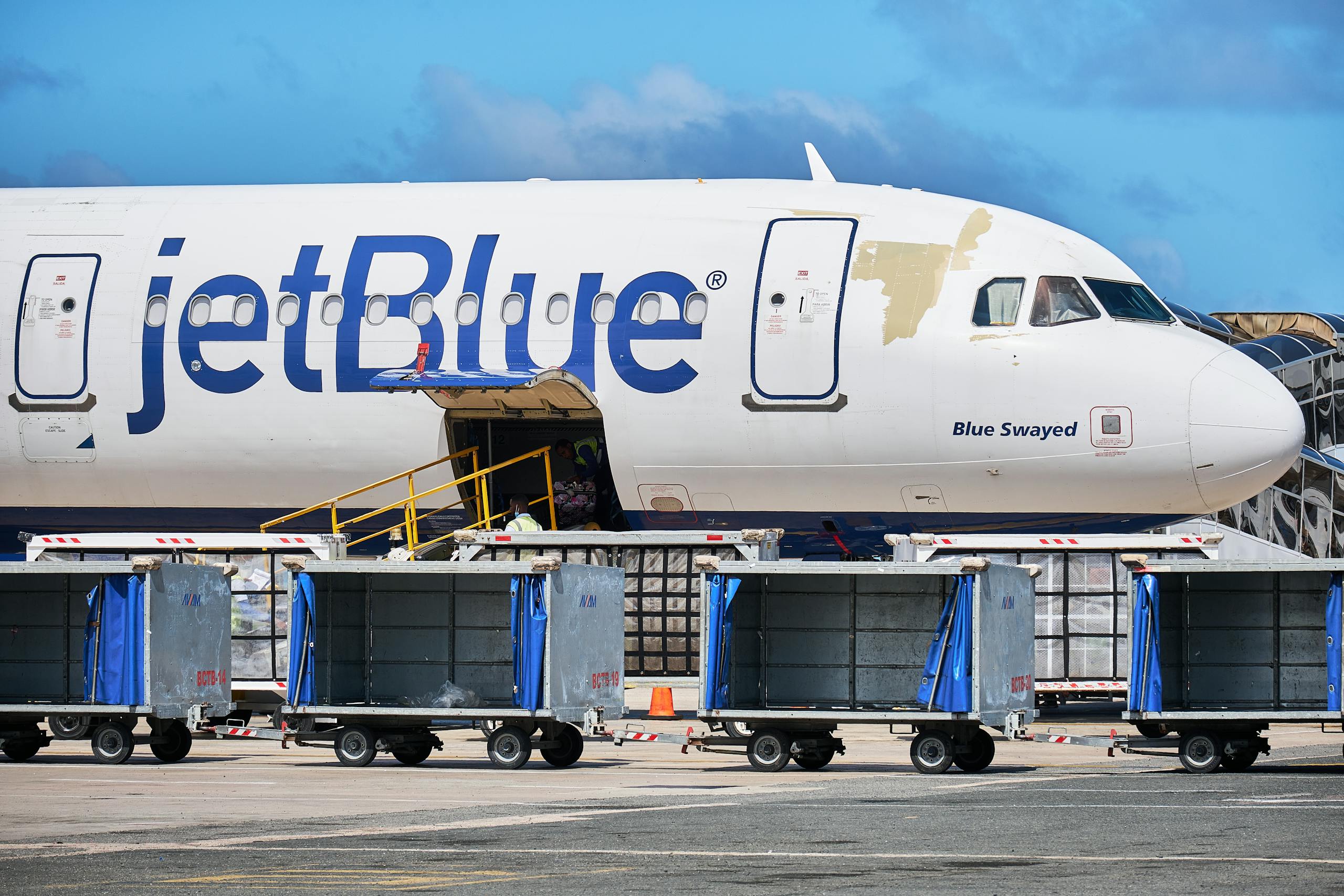 JetBlue Airbus with luggage carts at Punta Cana Airport, Dominican Republic.